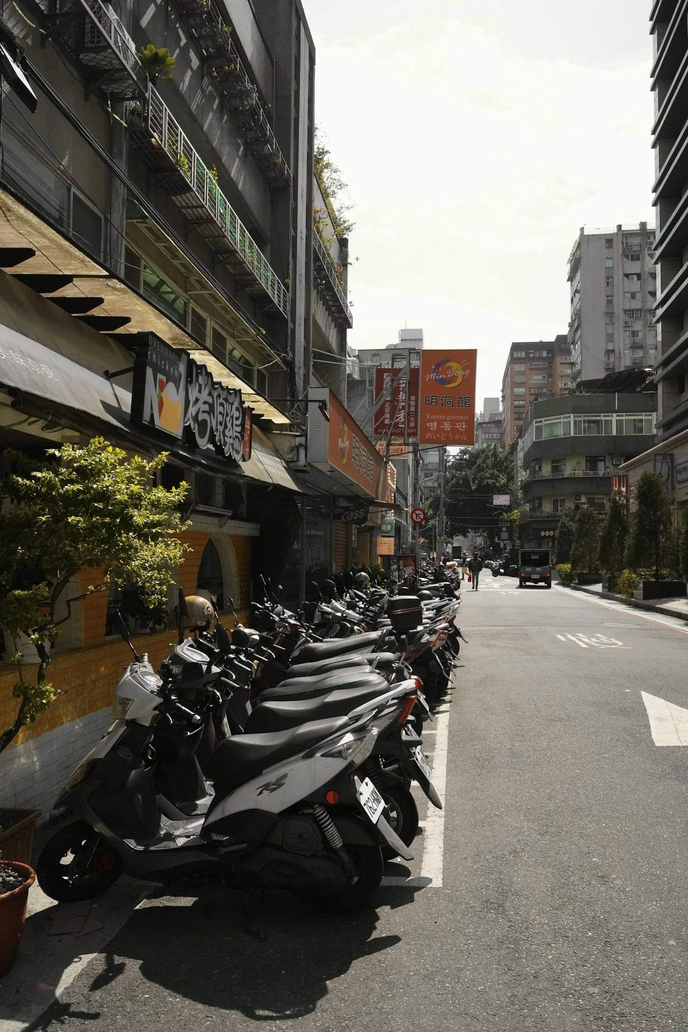 Row of two-wheelers parked along a street
